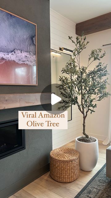 a living room with a tree in the corner and a large painting on the wall