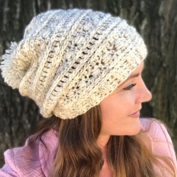 a woman wearing a white knitted hat next to a tree