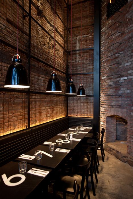 an empty restaurant with brick walls and black tablecloths on the dining room tables