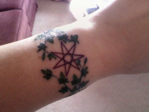 a person with a tattoo on their arm has a star and ivys around it