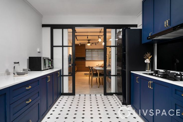 a kitchen with blue cabinets and white counter tops, black appliances and an open glass door leading to the dining room