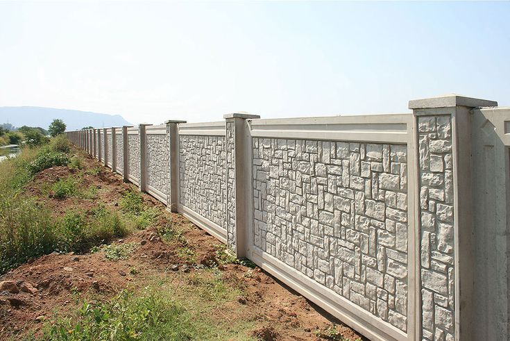 a row of stone blocks along the side of a road with grass growing on both sides