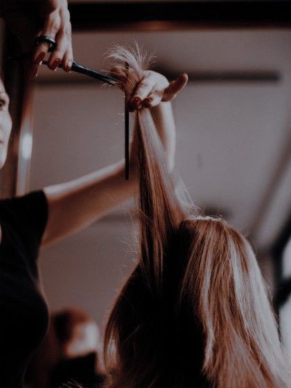 a woman is cutting her hair with scissors