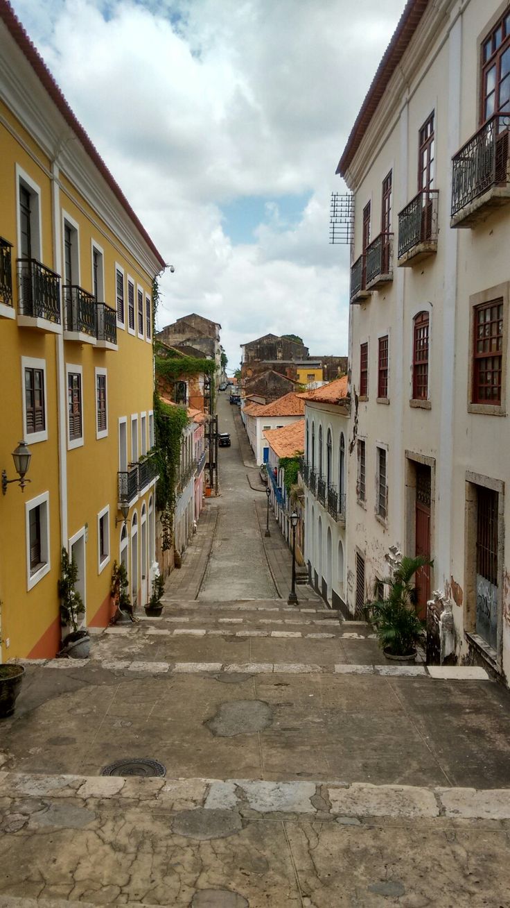 an empty street lined with tall buildings on both sides and balconies to the right