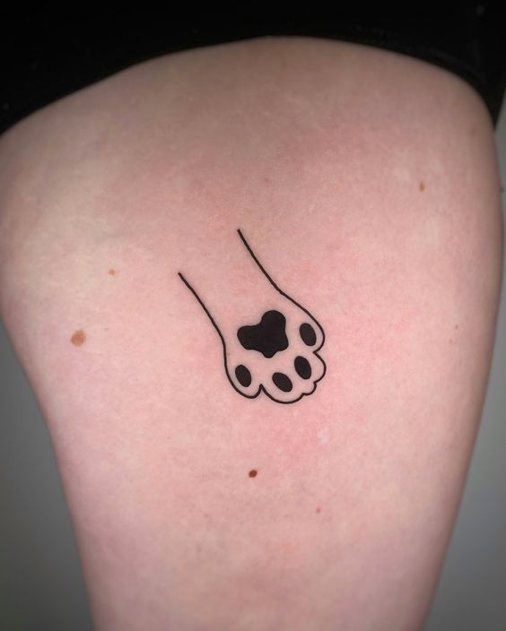 a dog paw tattoo on the back of a woman's thigh