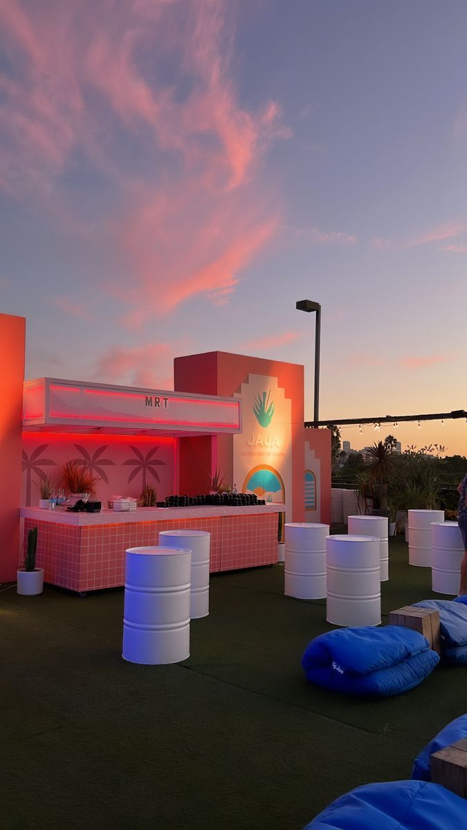 an outdoor event setup with blue and white barrels on the ground at sunset or dawn