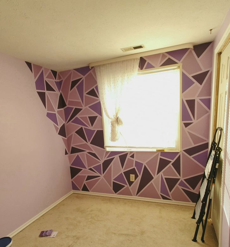 an empty room with purple and black geometric wallpaper on the walls, and a window in the corner