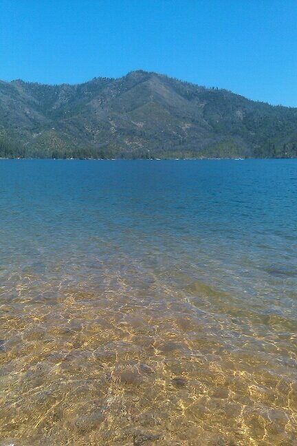 the water is crystal blue and clear with mountains in the background