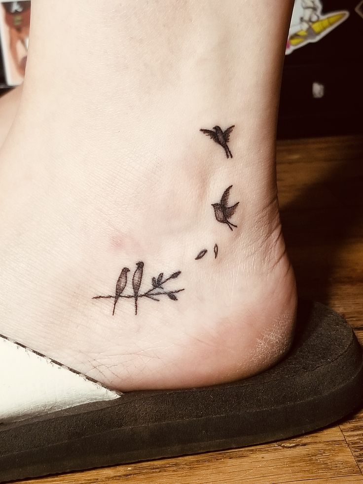 a small tattoo on the foot of a woman with birds flying above her feet,