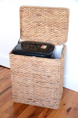 a wicker box with a cell phone in it on the floor next to a wall