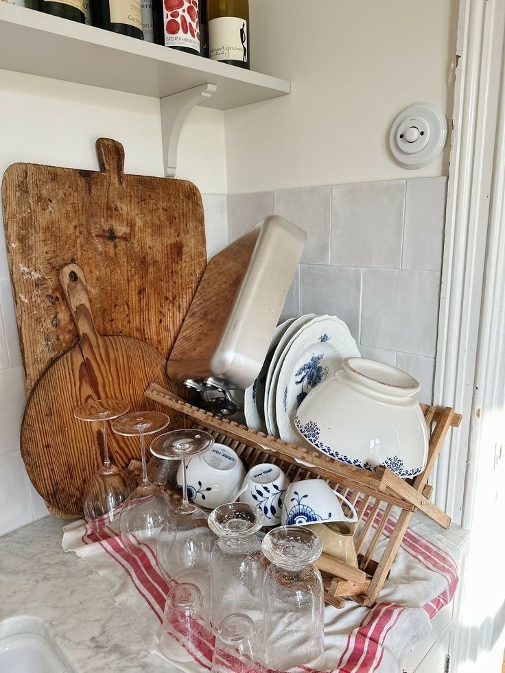 a wooden cutting board sitting on top of a kitchen counter next to dishes and glasses