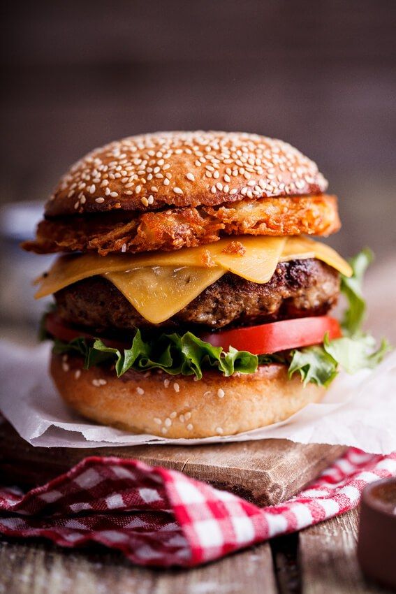 a cheeseburger with lettuce, tomato and onion on a wooden table