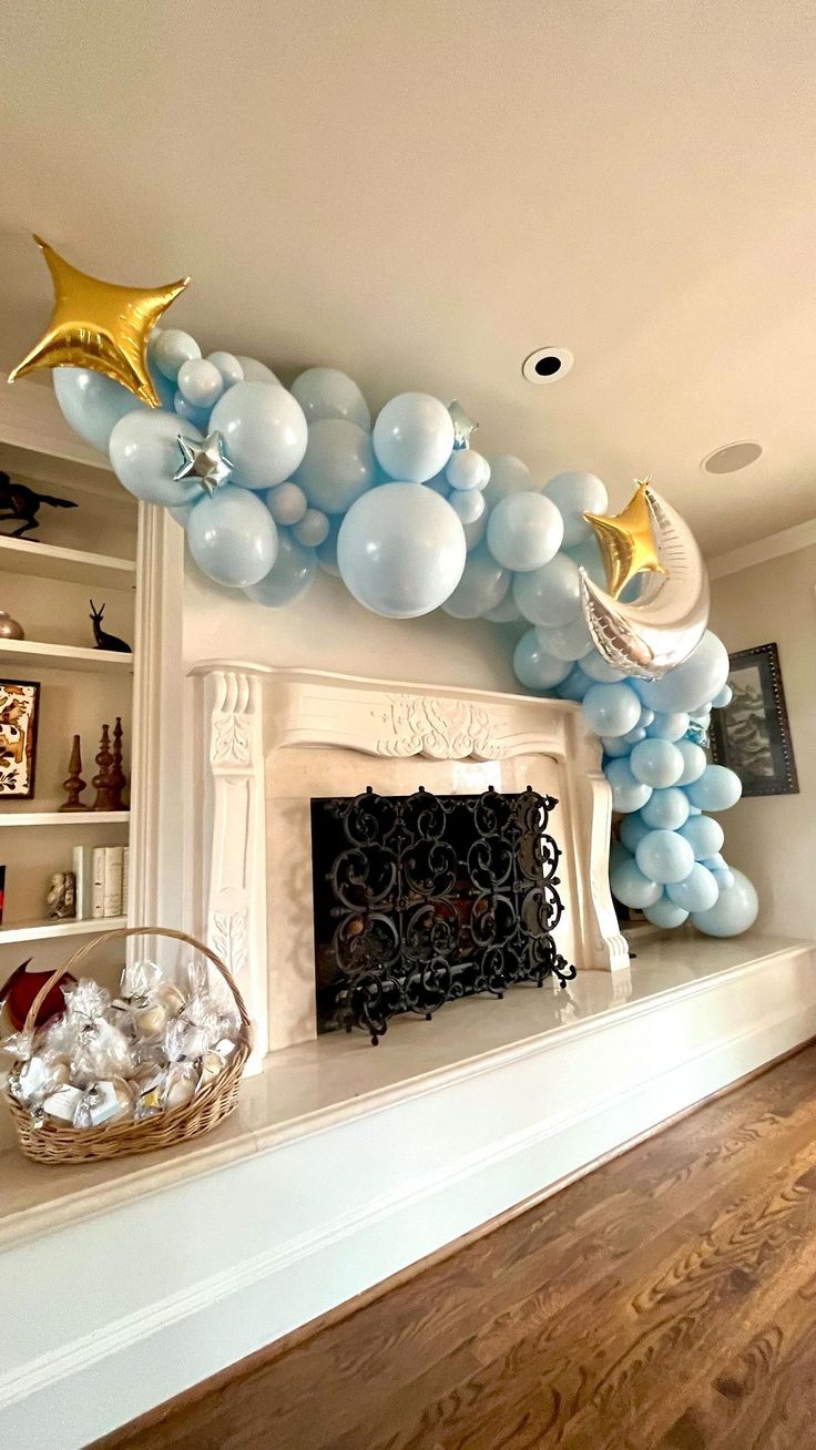 balloons and stars are hanging from the ceiling above a fireplace in a room with wood floors