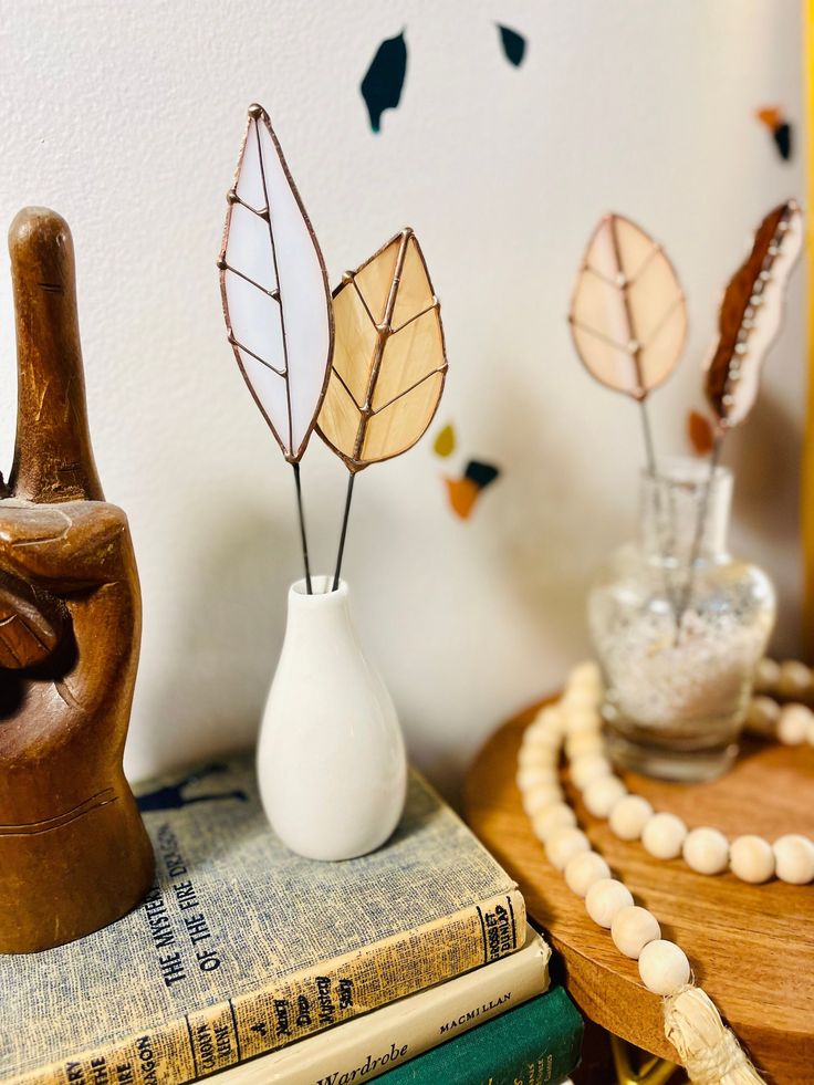 three decorative items sitting on top of a wooden table next to books and vases