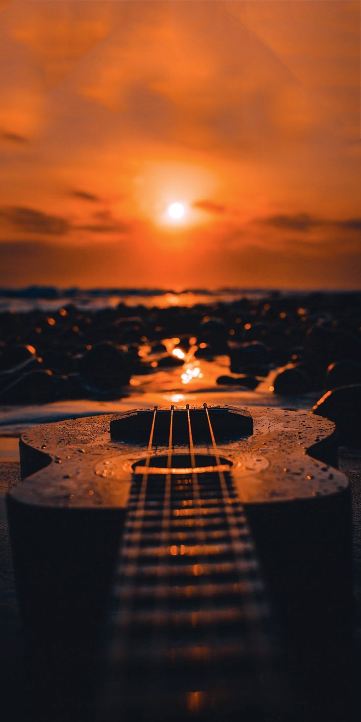 the sun is setting over an ocean with a surfboard