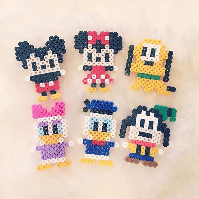 four mickey mouses made out of perler beads on a white surface with the same character in different colors