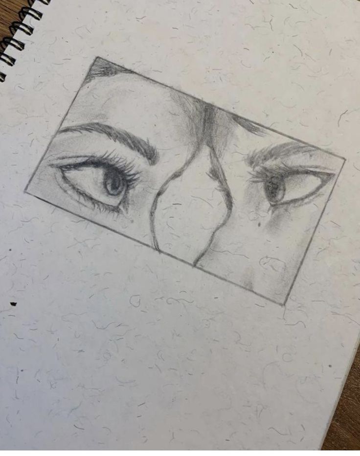 a pencil drawing of two eyes on top of a notebook