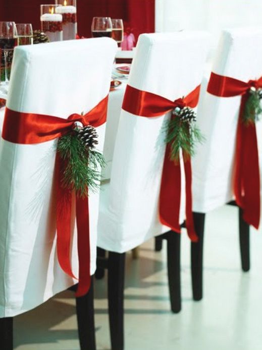 the chairs are covered with red ribbon and decorated with pinecone sprigs