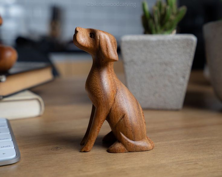 a wooden dog figurine sitting on top of a table next to a cell phone