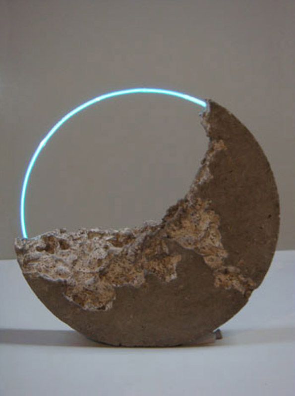 an object made out of concrete with a neon ring around it's center, sitting on a white surface