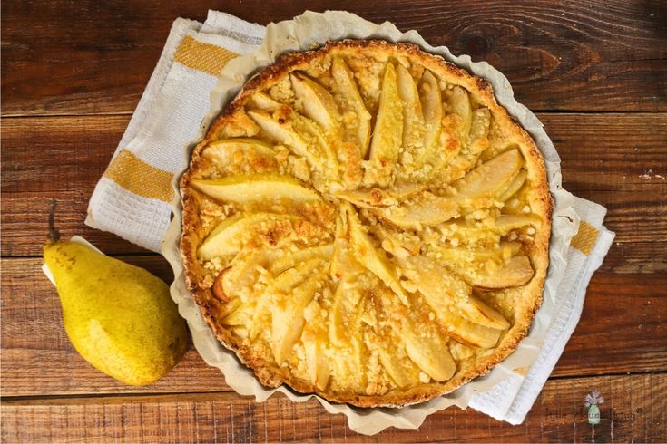 a pie sitting on top of a wooden table next to a pear