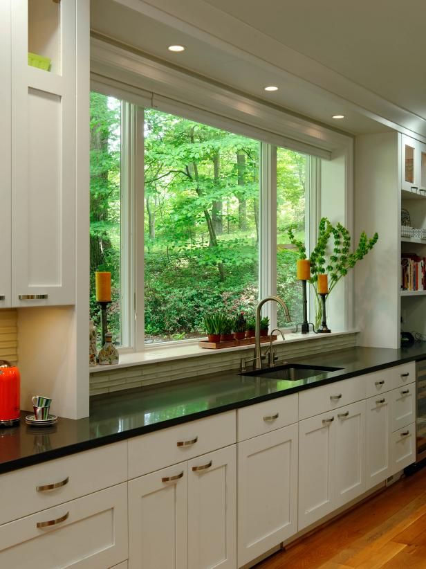 a kitchen filled with lots of white cabinets and counter top space next to a window