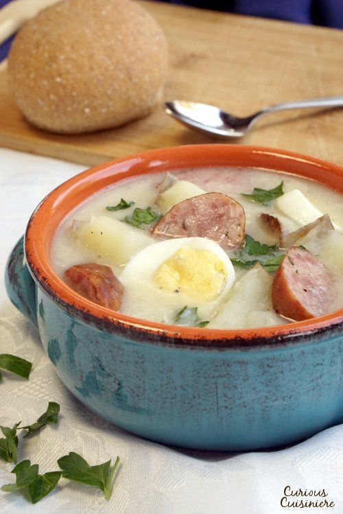 a blue bowl filled with soup next to a loaf of bread