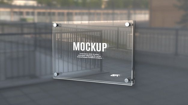 a glass sign with the words mock up on it in front of a fenced area