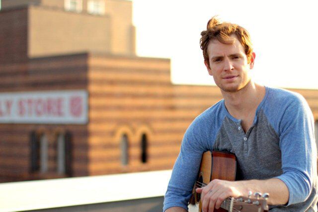 a man sitting on top of a roof holding a guitar