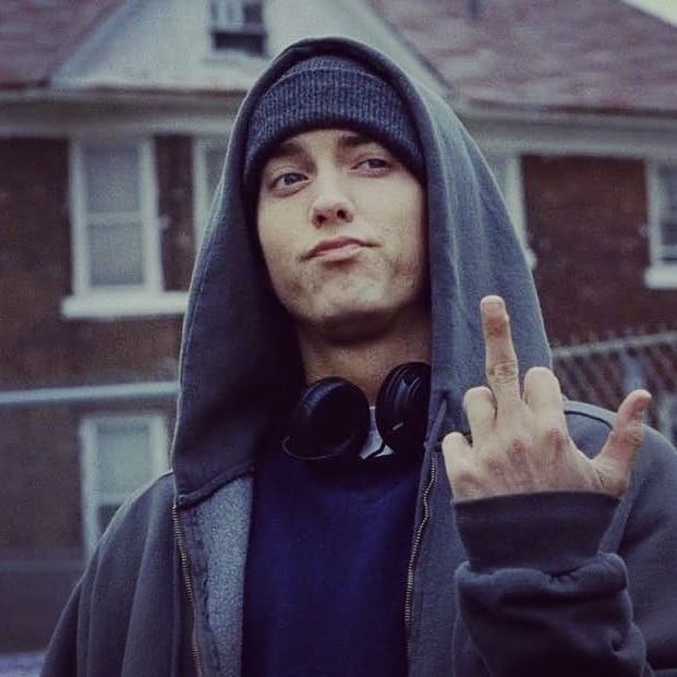 a man in a hoodie making the peace sign with his hand while wearing headphones