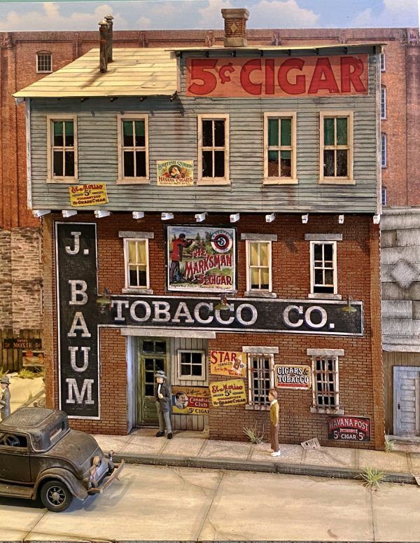 a painting of an old fashioned store on the side of a street with cars parked in front of it