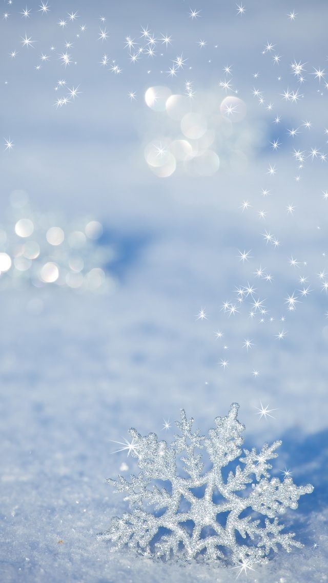 a snowflake that is sitting in the snow with sparkling stars above it and some water droplets