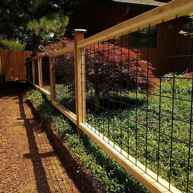 the fence is made of wood and has metal bars on each side, along with green grass