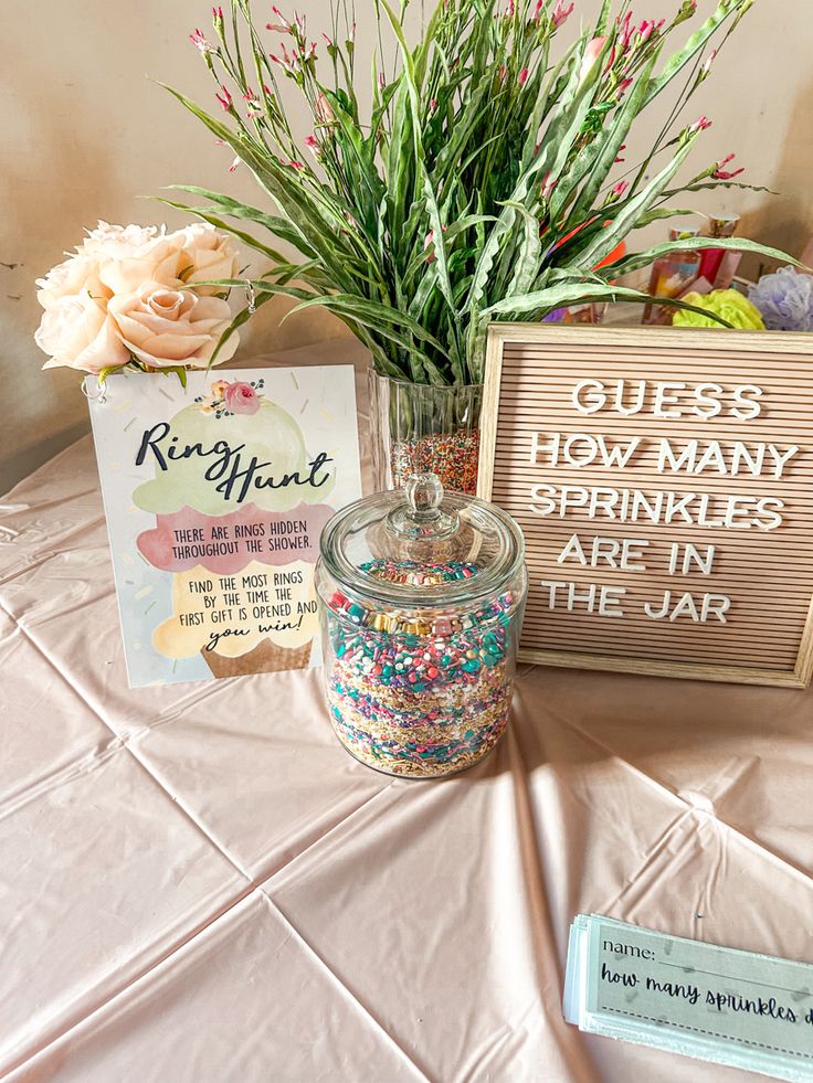 a table topped with a jar filled with sprinkles next to a sign