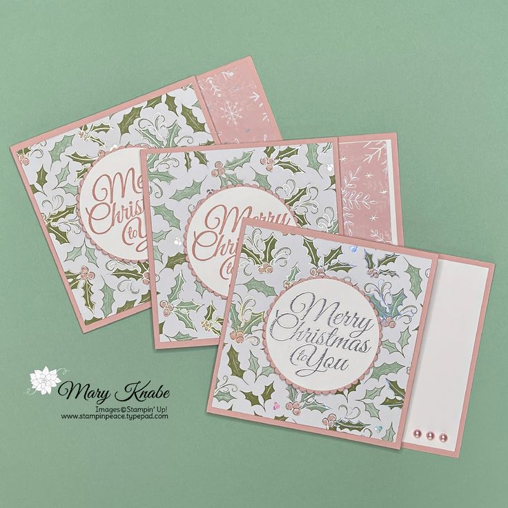 three christmas cards with holly designs on them, one is pink and the other is green