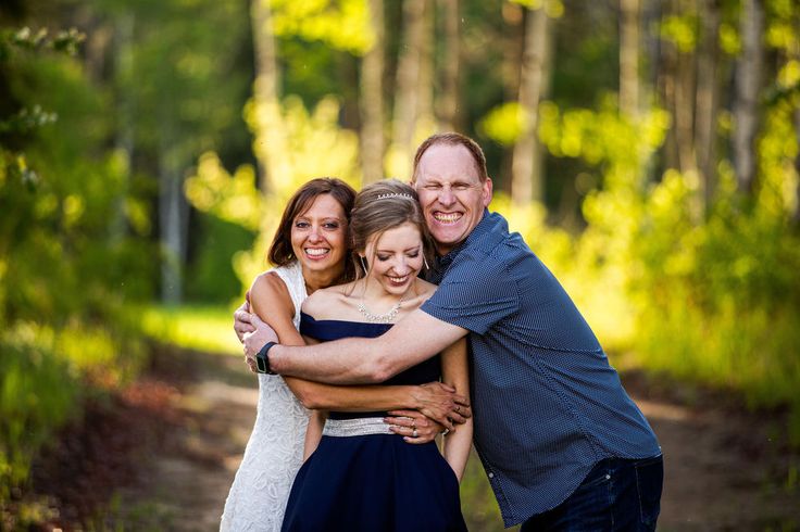 three people hugging each other in the woods