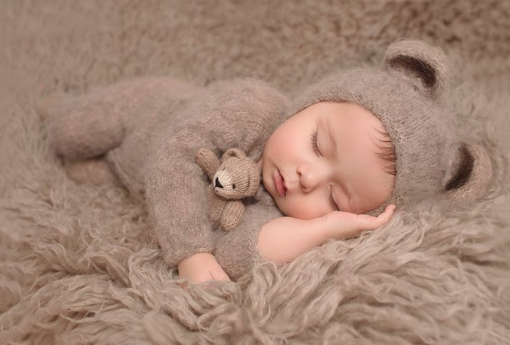 a baby is sleeping with a teddy bear