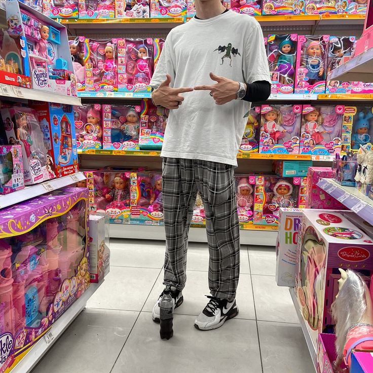 a young man standing in front of a store display filled with dolls and other toys