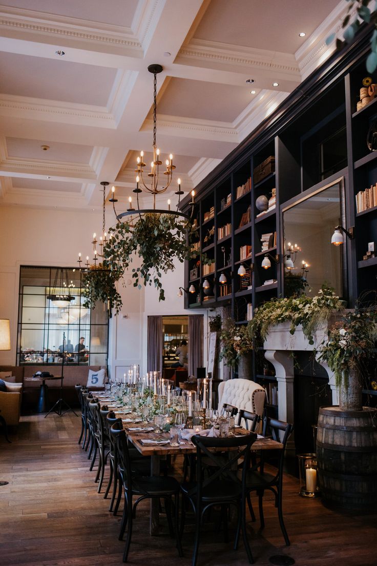 the dining room is decorated with greenery, candles and bookshelves for an elegant touch