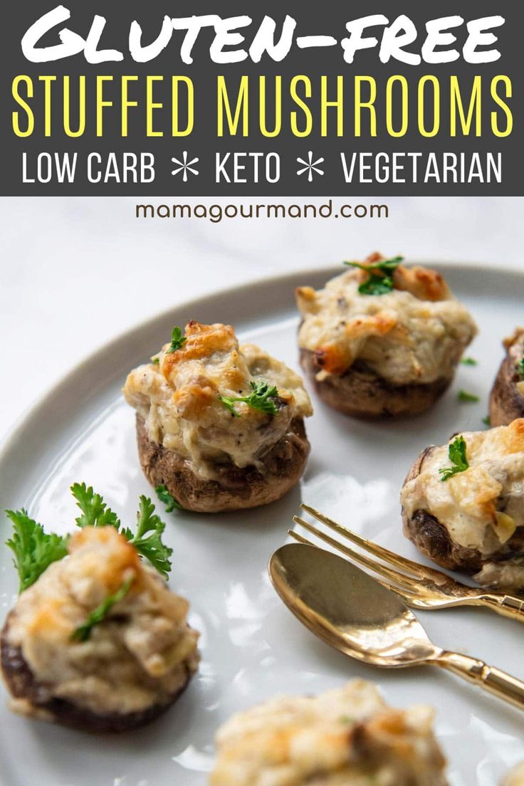 stuffed mushrooms with cheese and parsley on a white plate next to a gold fork