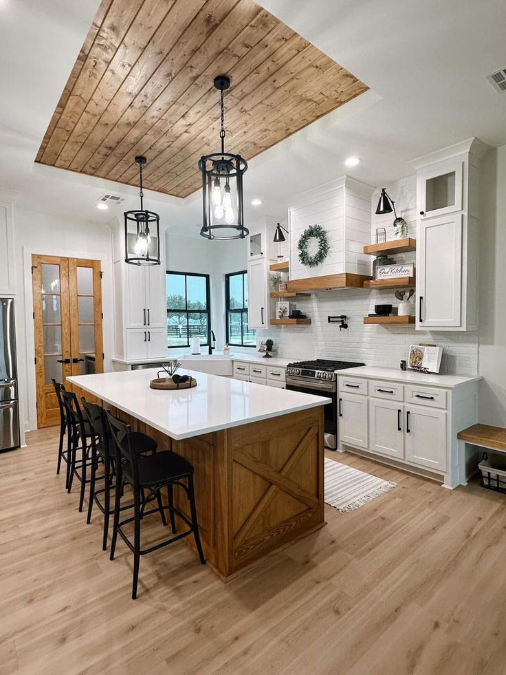 a large kitchen with white cabinets and wooden ceilinging, along with an island in the middle