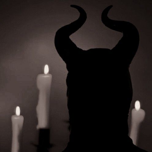 a black and white photo of candles with horns on them in front of a dark background