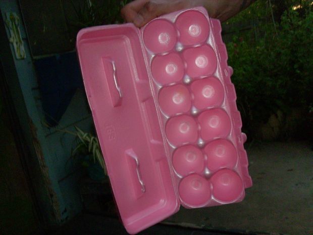 a person holding an egg carton filled with pink eggs