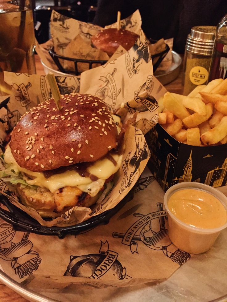 a burger and fries on a plate with some dipping sauces in the bowl next to it