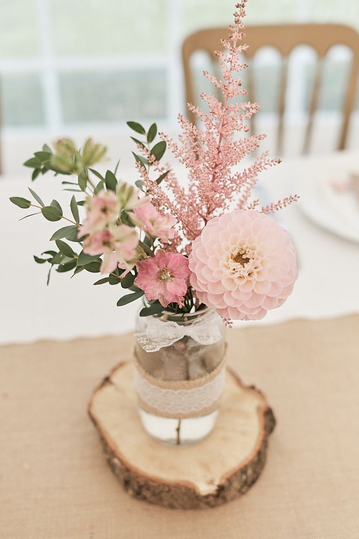 a vase filled with pink flowers on top of a wooden table next to a white plate