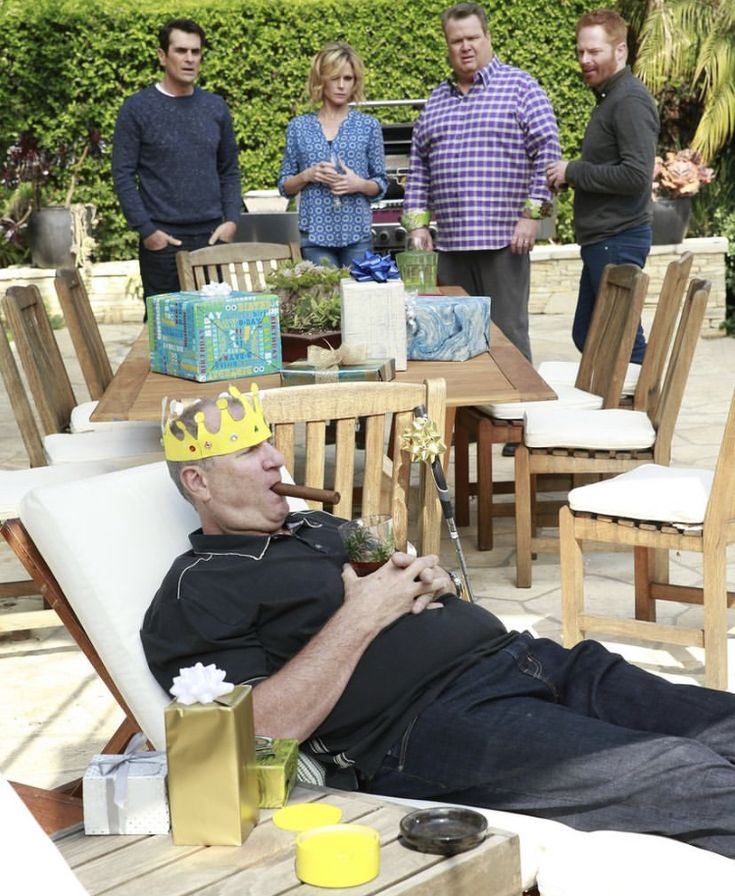 a man laying on top of a white chair next to a table filled with food