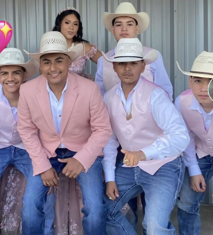 a group of men in cowboy hats posing for a photo with one man wearing a pink suit