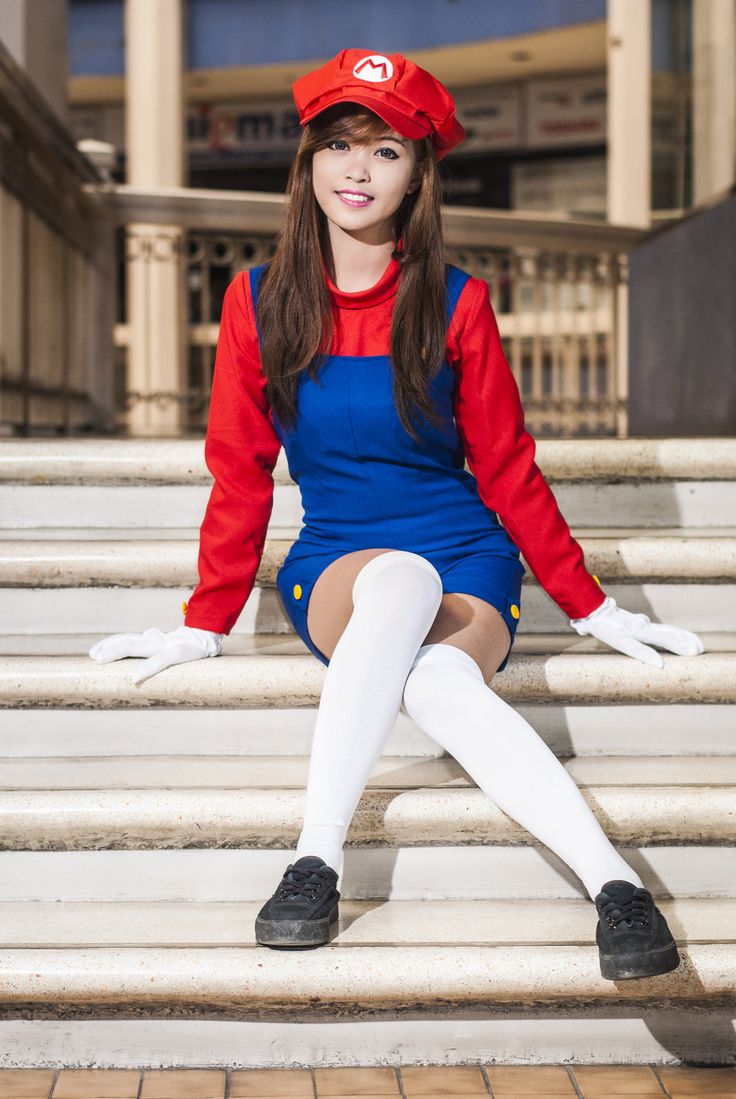 a woman in a red shirt and blue dress is sitting on some steps with her legs crossed