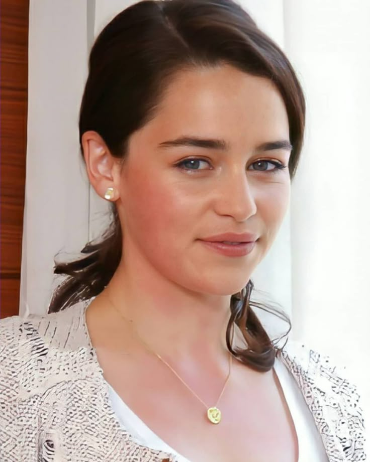 a woman wearing a white jacket and gold necklace