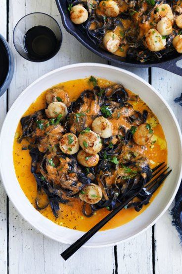 two bowls filled with shrimp and clams on top of a white table